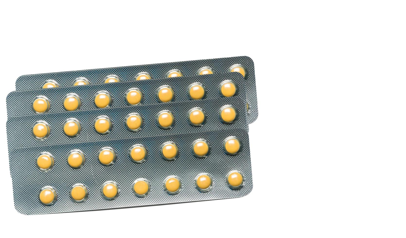 Rabeprazole Small round light yellow enteric-coated tablet pills in blister pack isolated on white background with copy space. Medicine for treatment gastric ulcer stomach ulcer or GERD. photo