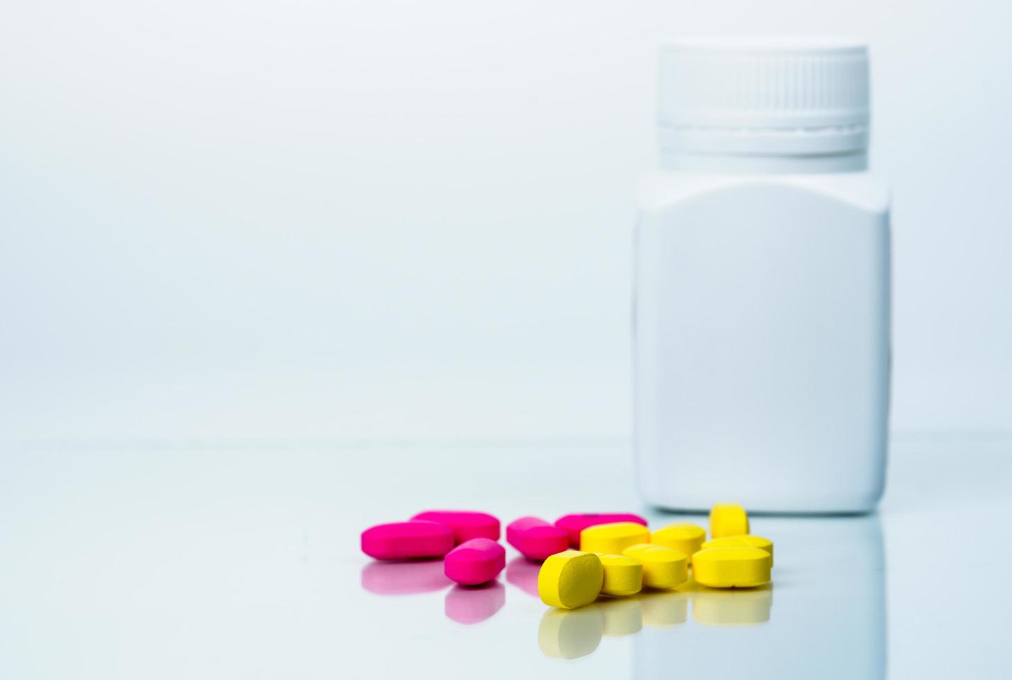 Yellow tablets pills blurred pink tablets and blank label drug bottle. Painkiller. Pharmaceutical industry. Pharmacy drugstore products. Medication use in hospital. Prescription drugs. Pharmacology. photo