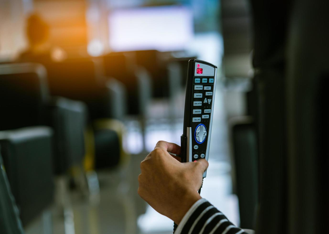 Asian woman use hand hold and press button on remote to control robotic massage chairs to relax head, shoulders, and back after work hard all day photo