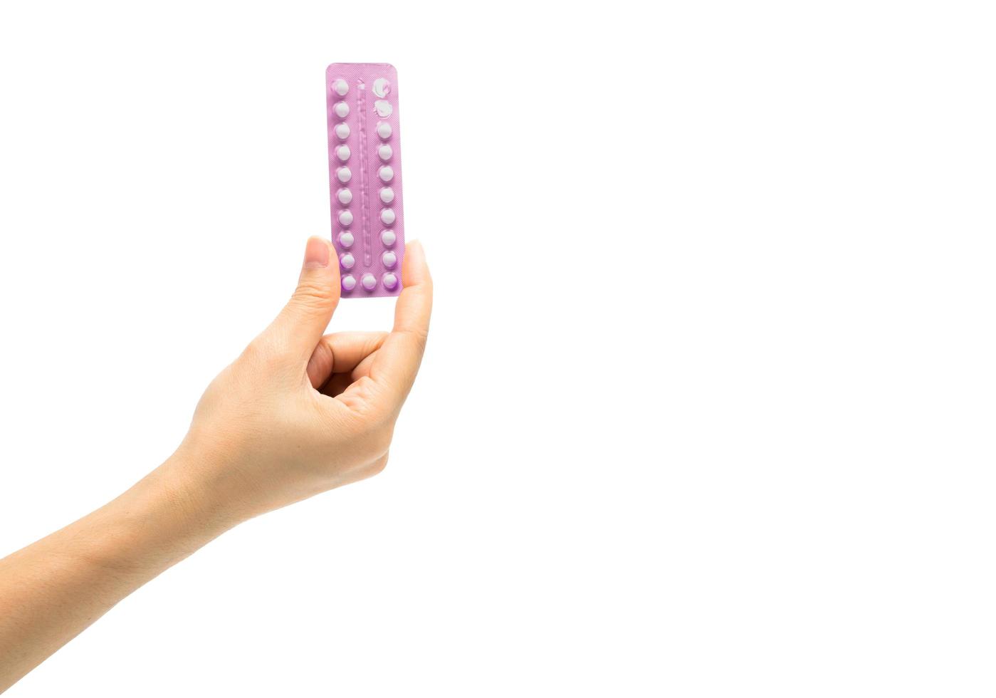 Asian young woman holding pack of contraceptive pills with one hand isolated on white background with copy space and clipping path. Choosing family planning with birth control pill concept photo