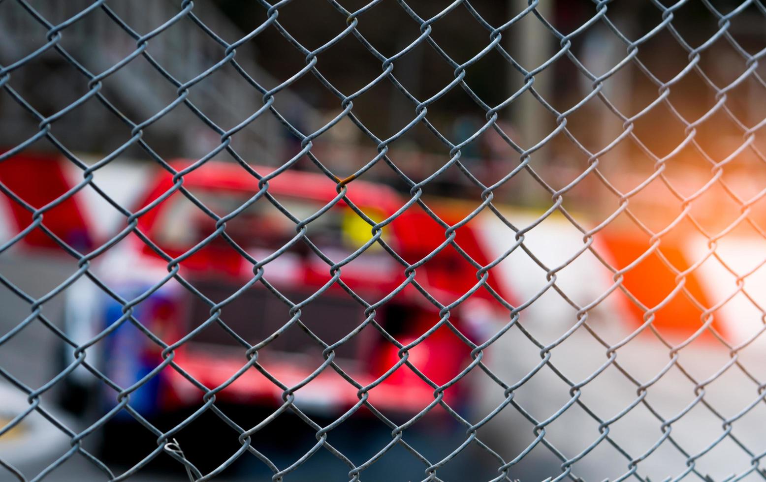 Motorsport car racing on asphalt road. View from the fence mesh netting on blurred car on racetrack background. Super racing car on street circuit. Automotive industry concept. photo