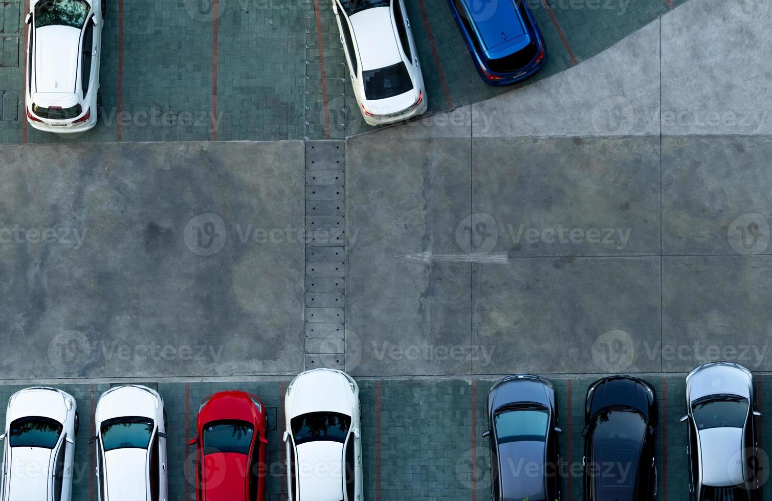 Top view concrete car parking lot. Aerial view of car parked at car parking area of apartment. Outdoor parking space with empty slot. One way traffic sign on road. Above view outside car parking lot. photo