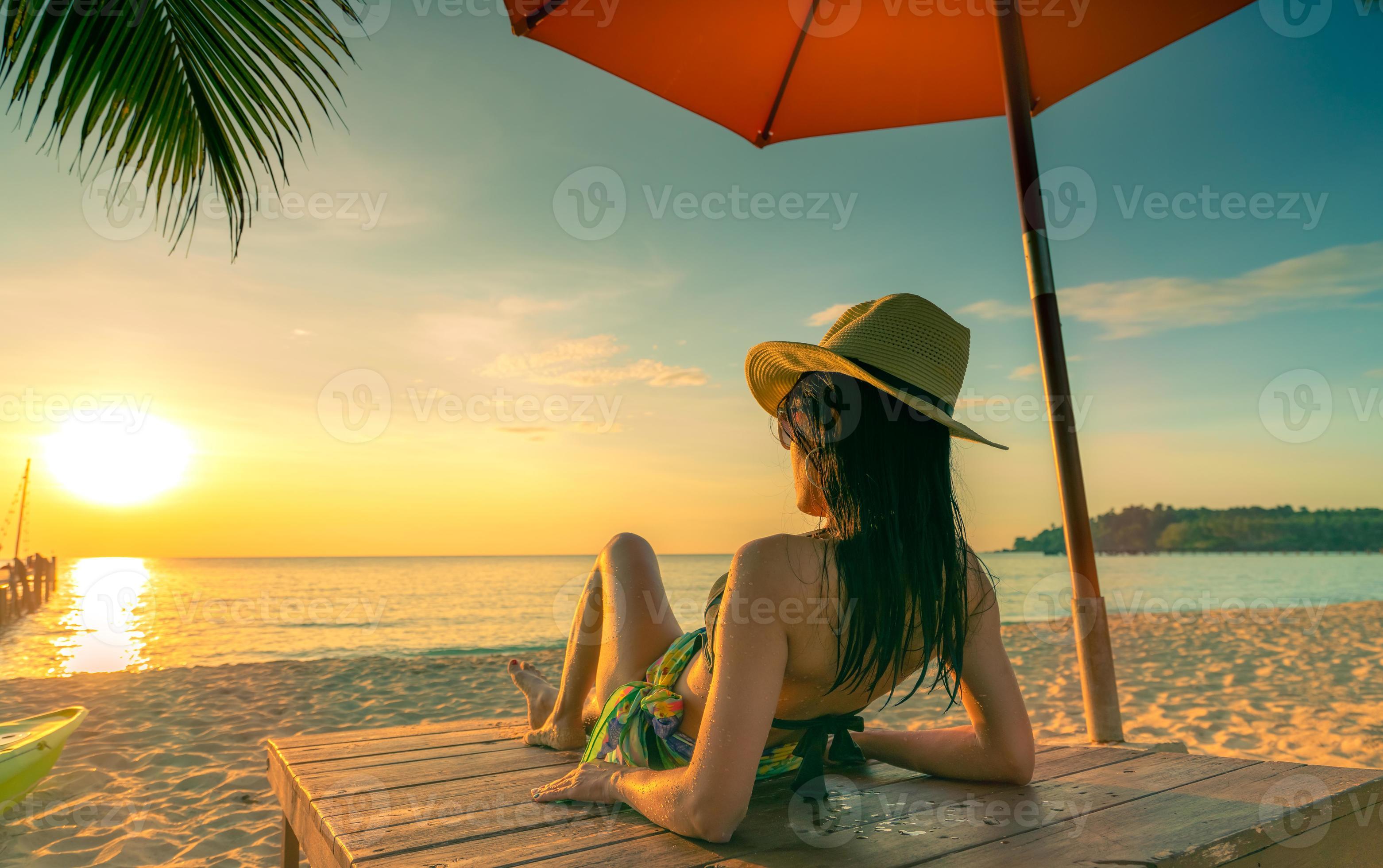 Sexy, enjoy and relax woman wear bikini lying and sunbathing on sunbed at  sand beach at paradise tropical island under beach umbrella at sunset.  Summer vacation. Holiday travel. Summer vibes. 7761425 Stock