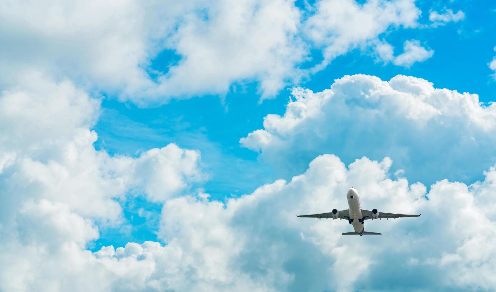 Commercial airline flying on blue sky and white fluffy clouds. Under view of airplane flying. Passenger plane after take off or going to landing flight. Vacation travel abroad. Air transportation. photo