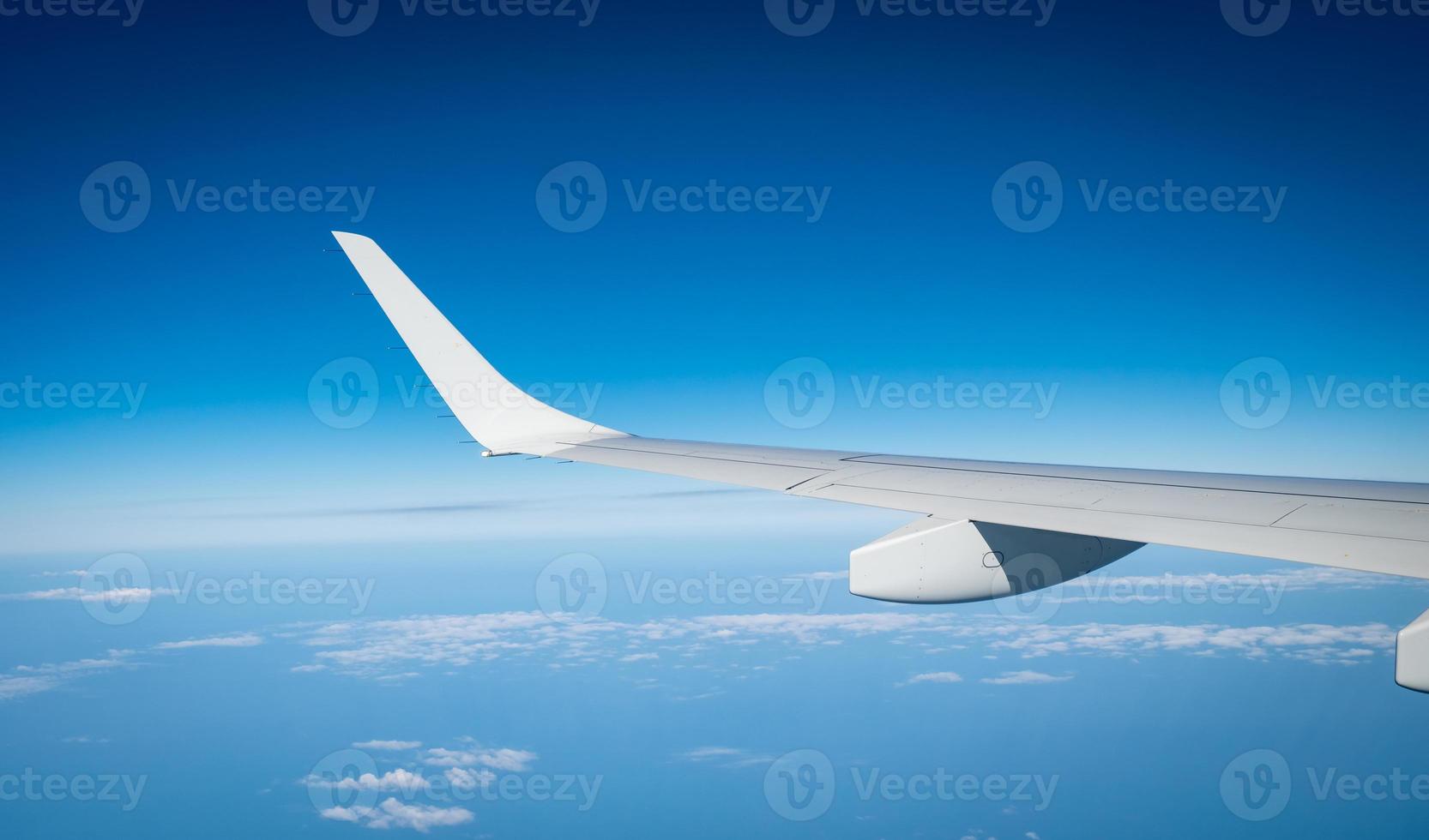 Wing of plane over white clouds. Airplane flying on blue sky. Scenic view from airplane window. Commercial airline flight. Plane wing above clouds. Flight mechanics concept. International flight. photo