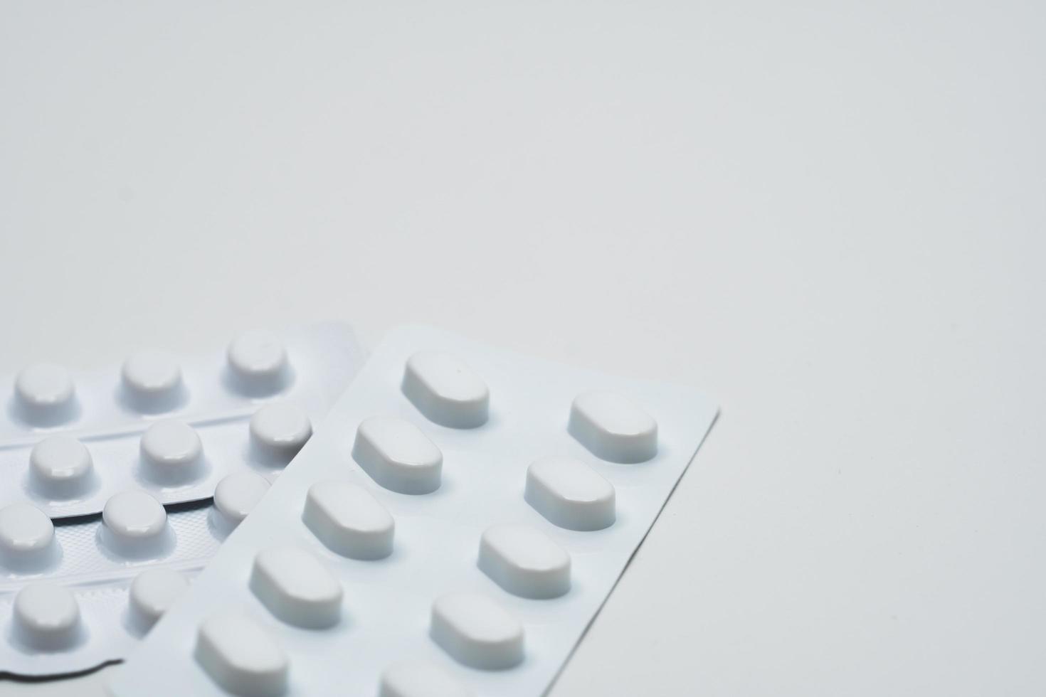 Macro shot detail of tablets pill in white blister pack for light resistance packaging isolated on white background. Medicine for treatment NCDs. Elderly people disease. photo