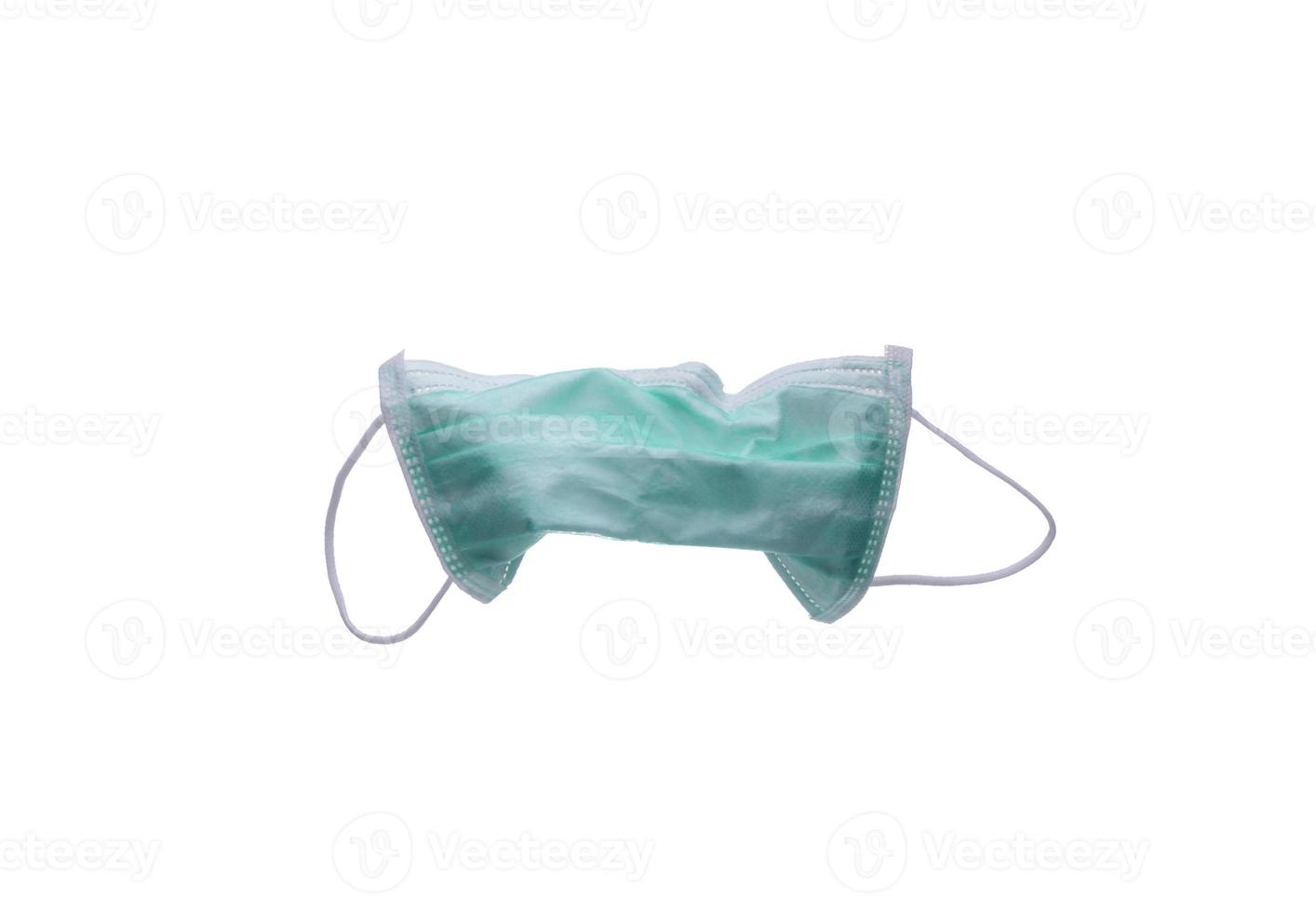 Used green surgical face mask isolated on white background with copy space. Medical waste. Infectious waste from coronavirus crisis. Green earloop medical face mask waiting for disposal with hygienic. photo