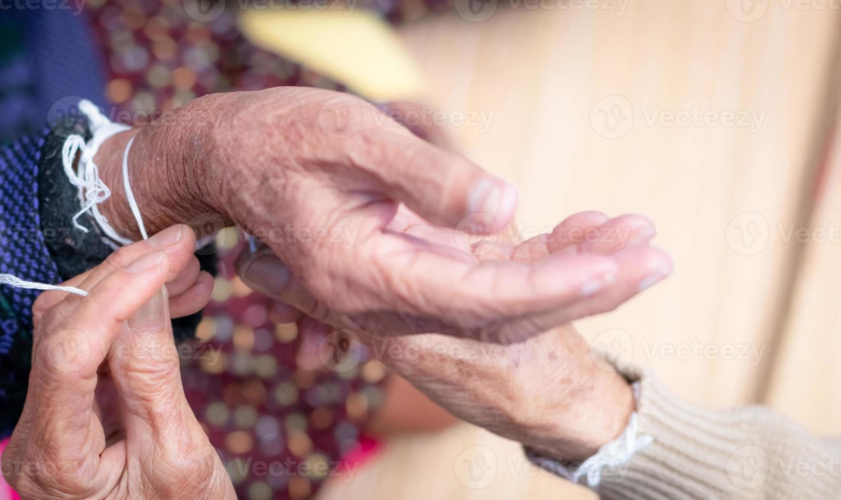 The ceremony of binding elderly people wrist with the holy thread to console old people's Kwan. Thai culture. Beliefs and local culture of Northeastern Thai people. Aging society in Southeast Asia. photo