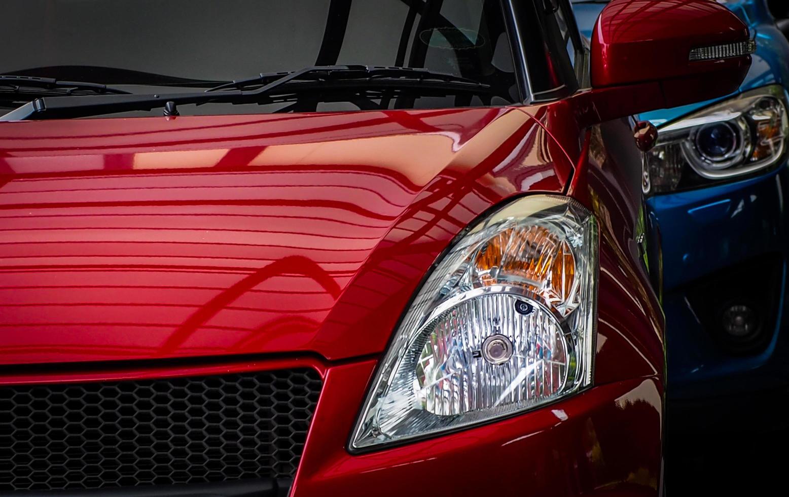Close up headlamp light of red shiny SUV car parked on concrete parking lot of the hotel or shopping mall. Automotive industry concept. Electric or hybrid car technology. Car rental and dealership. photo