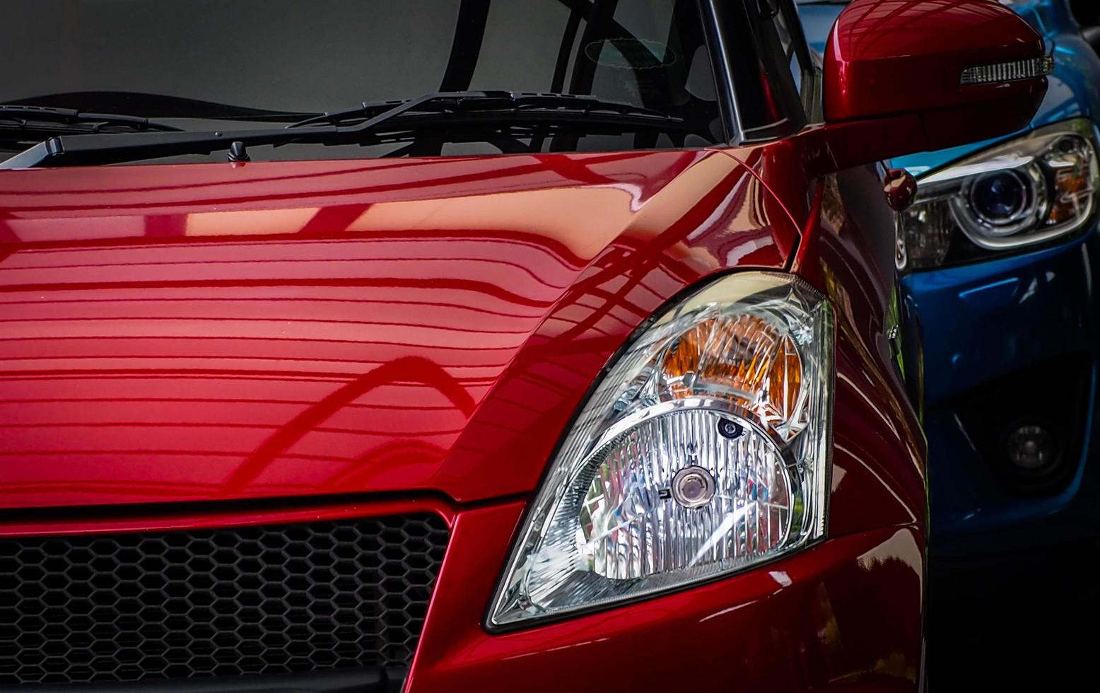 cierre la luz de los faros de un vehículo suv rojo brillante estacionado en un estacionamiento de concreto del hotel o centro comercial. concepto de industria automotriz. tecnología de coches eléctricos o híbridos. alquiler de coches y concesionario. foto