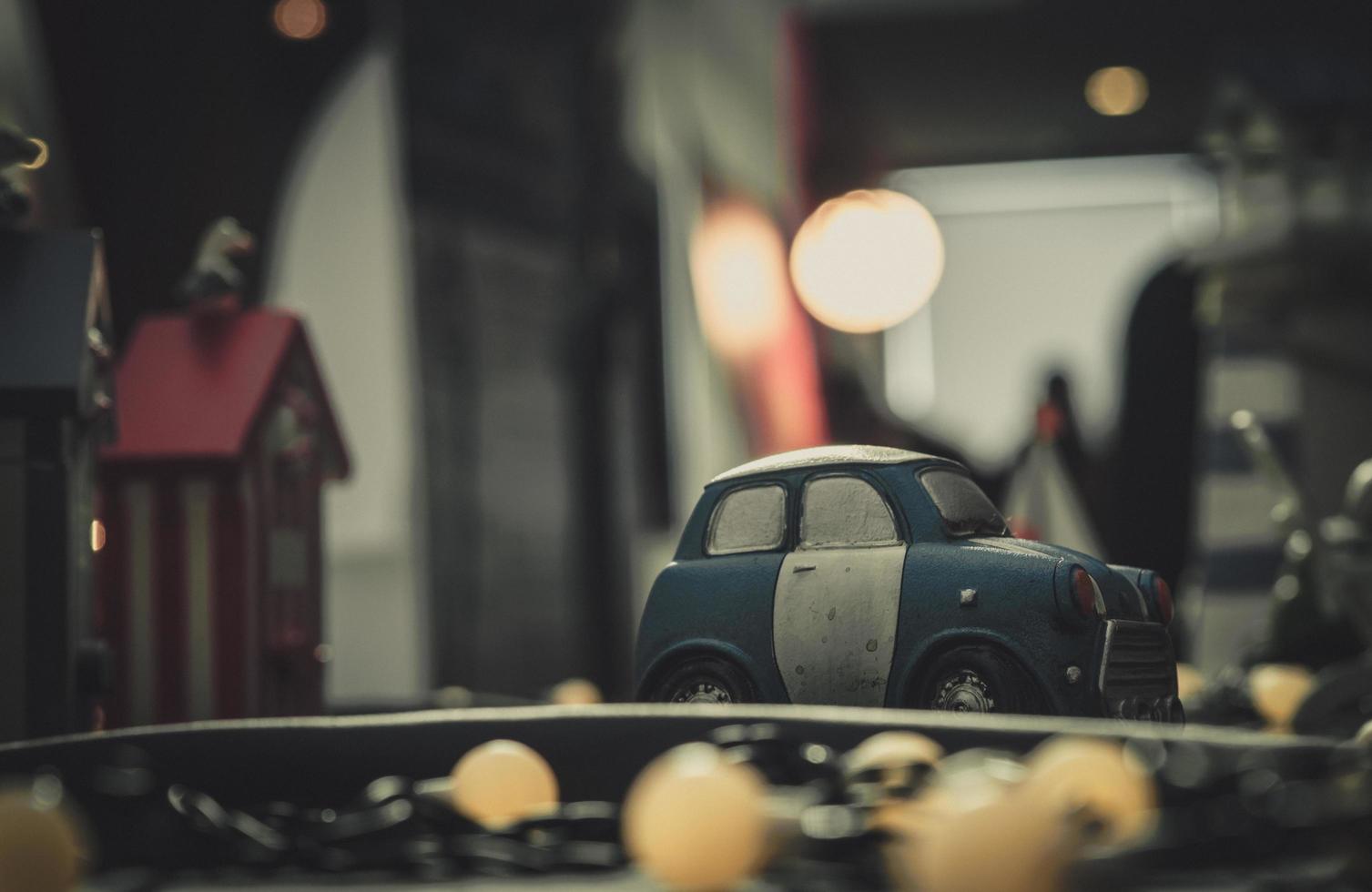 modelo de juguete de coche pequeño azul y blanco en la carretera. mini coche de juguete en la ciudad cerca del edificio sobre fondo borroso con bokeh. coche en miniatura de dibujos animados. mundo de la imaginación. noche de citas romanticas. foto