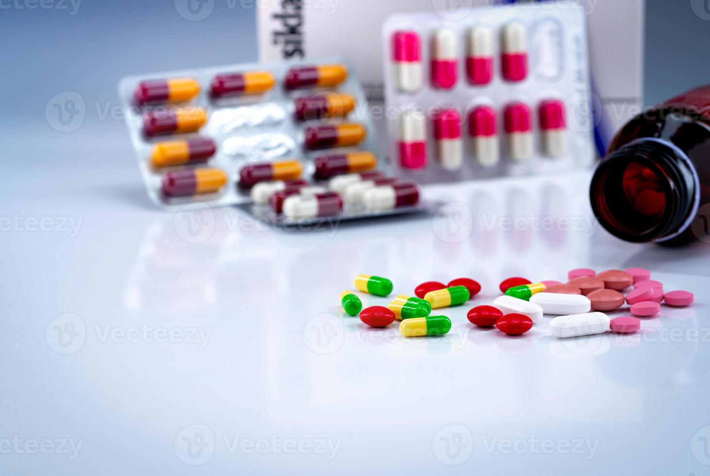 tabletas y cápsulas píldoras sobre mesa blanca y frasco de medicamento borroso, blister y caja de medicamento antibiótico. pastillas de colores. industria farmacéutica. productos de farmacia muchas de las píldoras de cápsulas y tabletas. foto