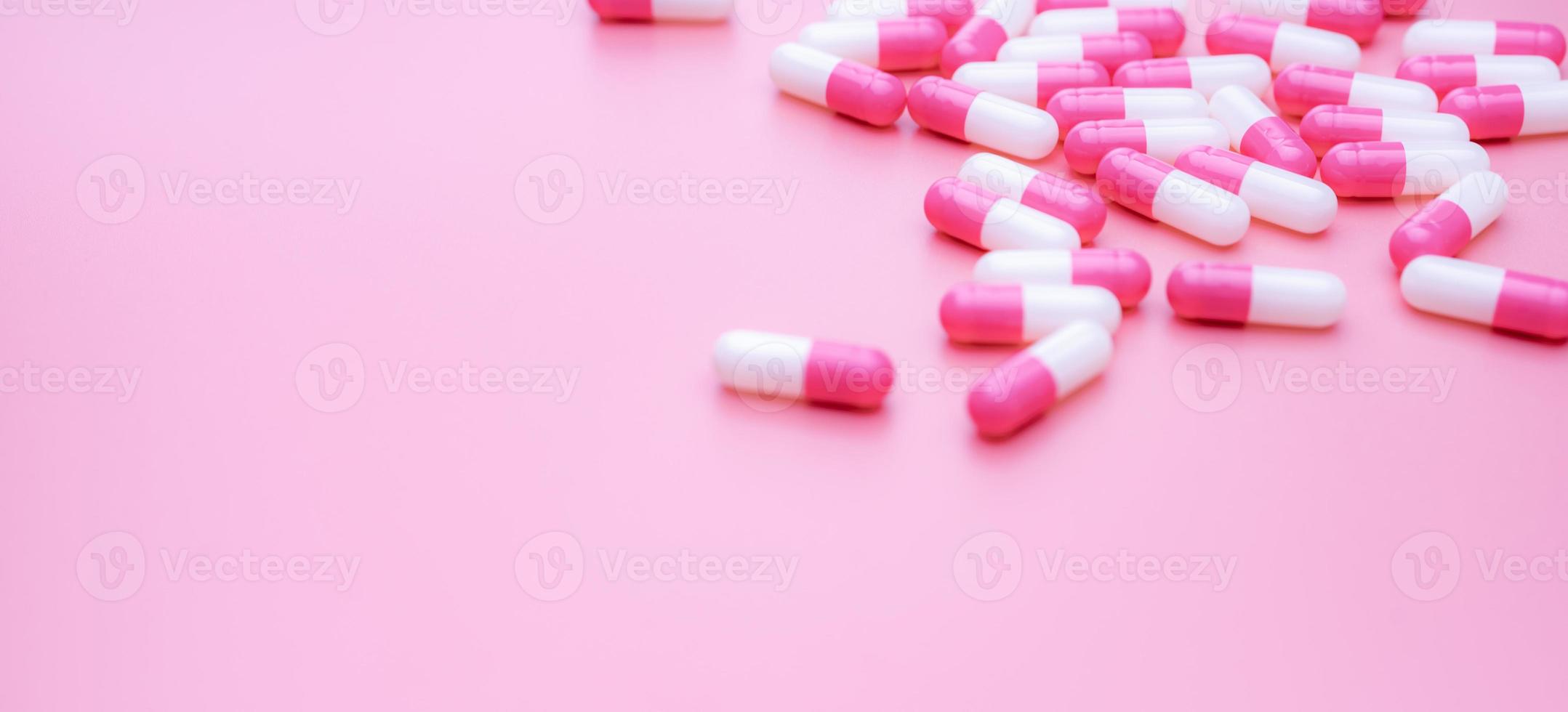píldoras de cápsula antibiótica de color rosa-blanco sobre fondo rosa. resistencia a los antibióticos. pastillas de cápsula esparcidas sobre fondo rosa. uso de medicamentos en el hospital. medicamentos con receta. Uso inteligente de antibióticos. foto