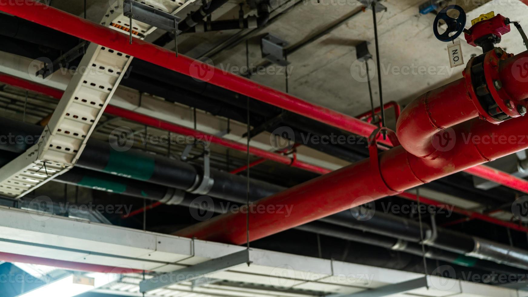 sistema de rociadores contra incendios con tuberías rojas que cuelgan del techo dentro del edificio. supresión de incendios. detector y protección contra incendios. tubería principal de suministro de agua en el sistema de extinción de incendios en el hospital. foto