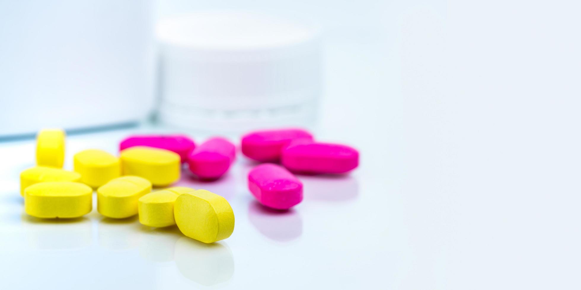 Yellow tablets pills blurred pink tablets and drug bottle. Painkiller. Pharmaceutical industry. Pharmacy drugstore products. Medication use in hospital. Pharmacology. Prescription drugs. Healthcare. photo