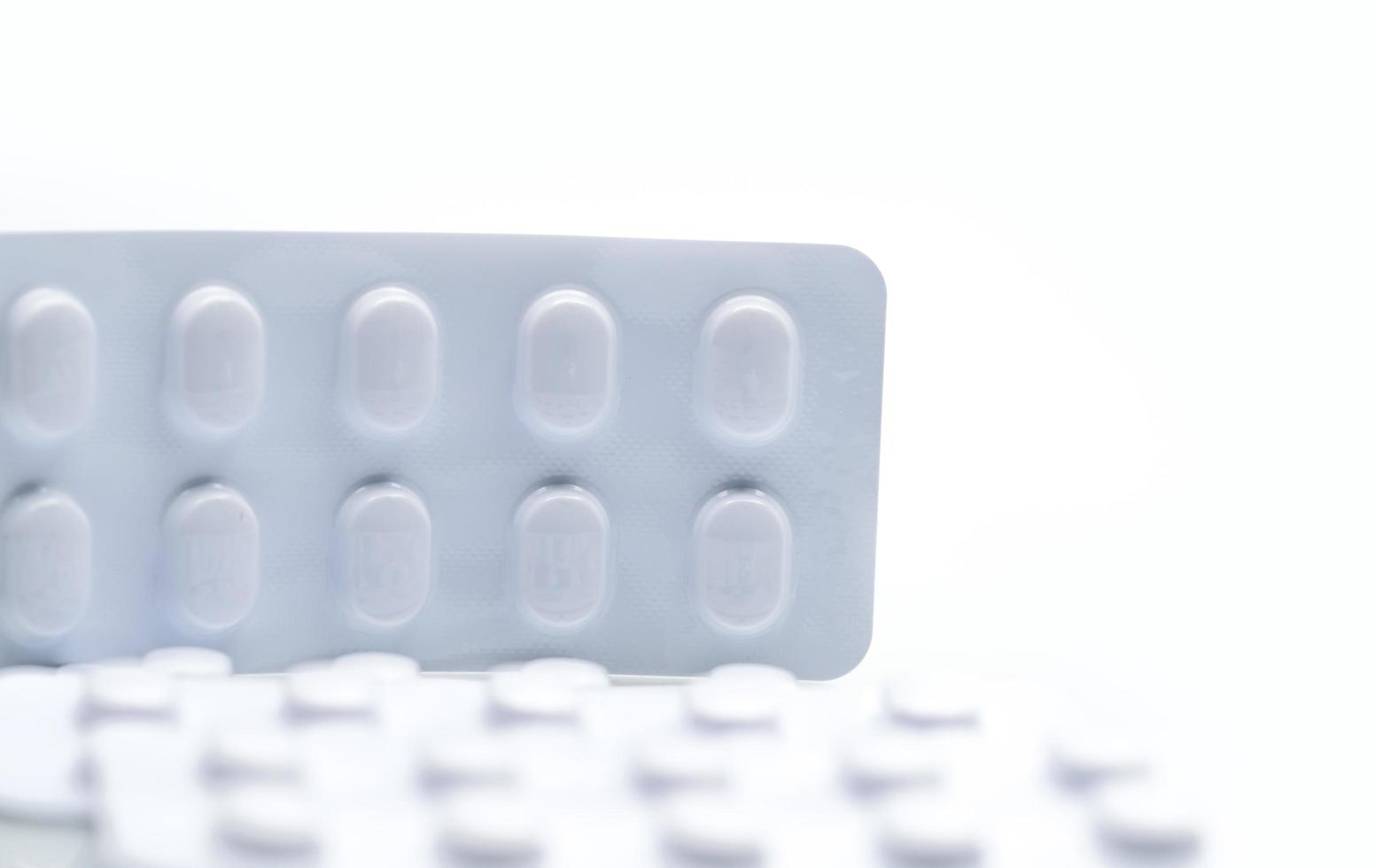 Macro shot detail of tablets pill in white blister pack for light resistance packaging isolated on white background. Medicine for treatment NCDs. Elderly people disease. photo