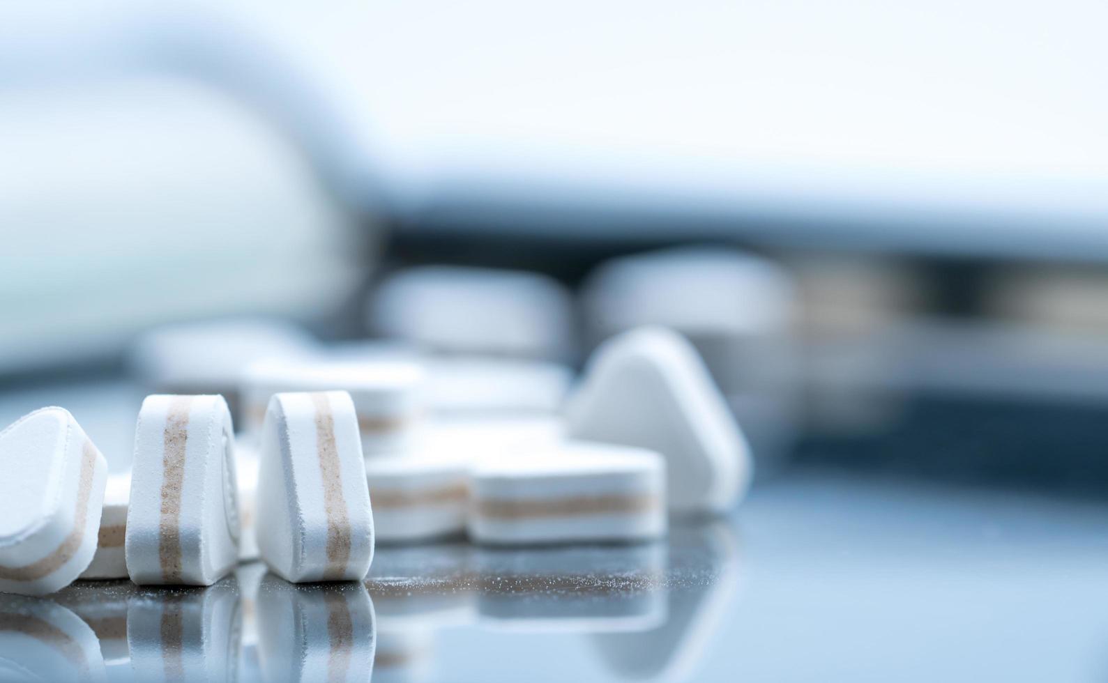 Macro shot of triangle shape tablet pills. Three layers tablet pills for indication antacid, digestive and gastric pain. Group of sandwich tablets pills on stainless steel drug tray. photo