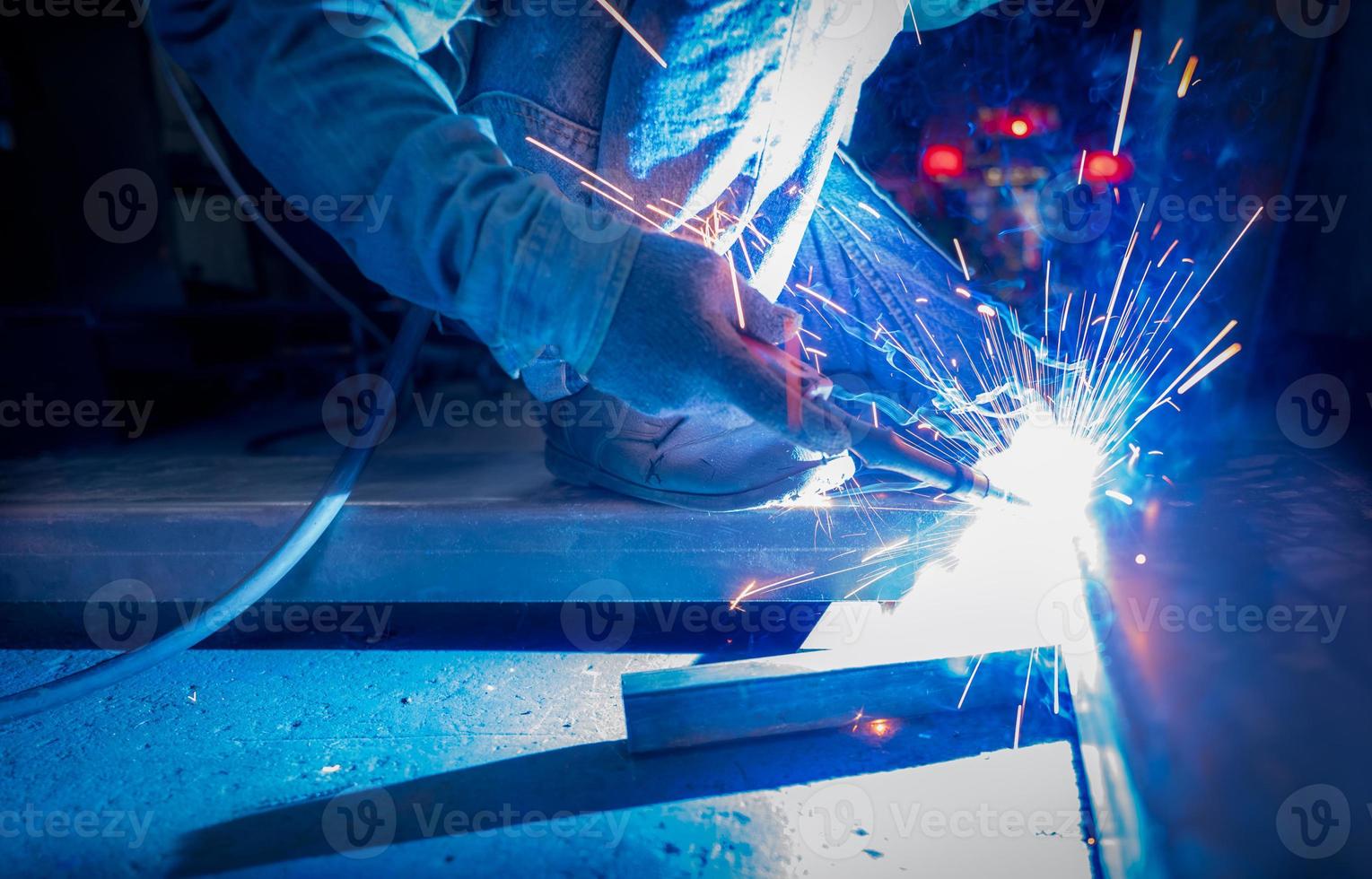 Welder welding metal with argon arc welding machine and has welding sparks. A man wears protective gloves. Safety in industrial workplace. Welder working with safety. Worker in steel industry factory. photo