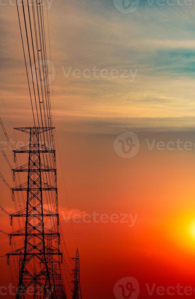 High voltage electric pole and transmission lines in the evening. Electricity pylons at sunset. Power and energy. Energy conservation. High voltage grid tower with wire cable at distribution station. photo