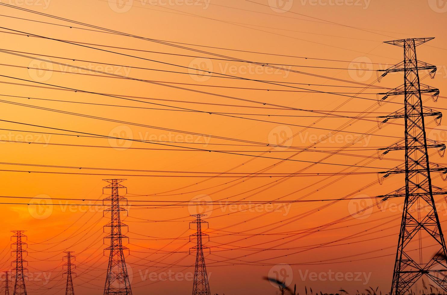 Silhouette high voltage electric pylon and electrical wire with an orange sky. Electricity poles at sunset. Power and energy concept. High voltage grid tower with wire cable at distribution station. photo
