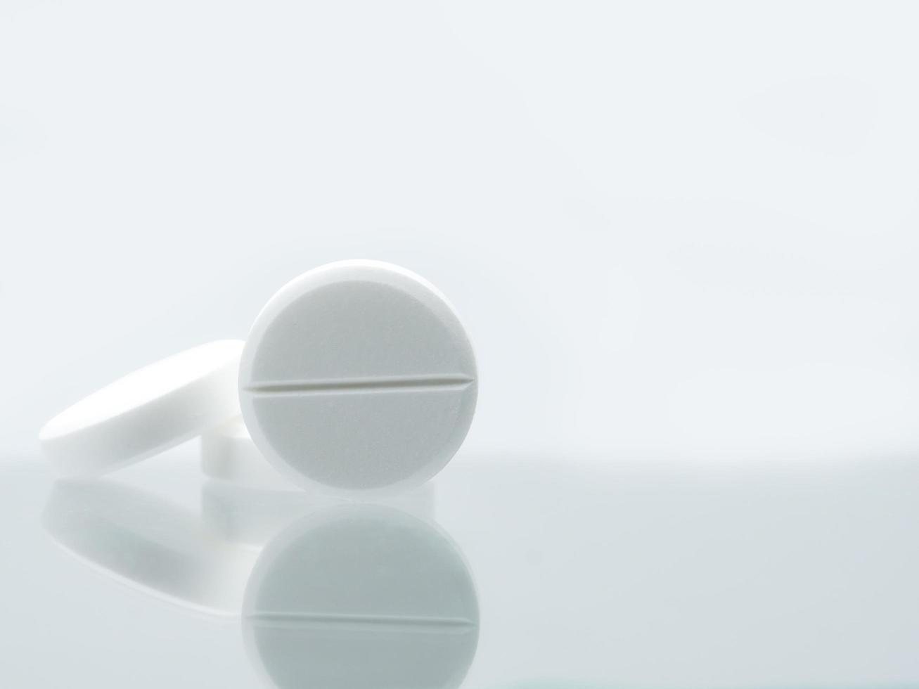 Macro shot of three white chewable tablets on white background with shadows. Antacids pills for relief stomachache from excess gastric acid in stomach. Stress induce gastric ulcer treatment concept. photo