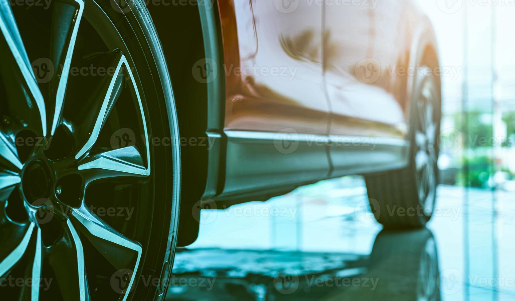 Luxury car parked in modern showroom. Auto leasing business. Car dealership concept. Closeup wheel of red shiny car show in showroom. Automotive industry. Auto glass coating and shinning business. photo