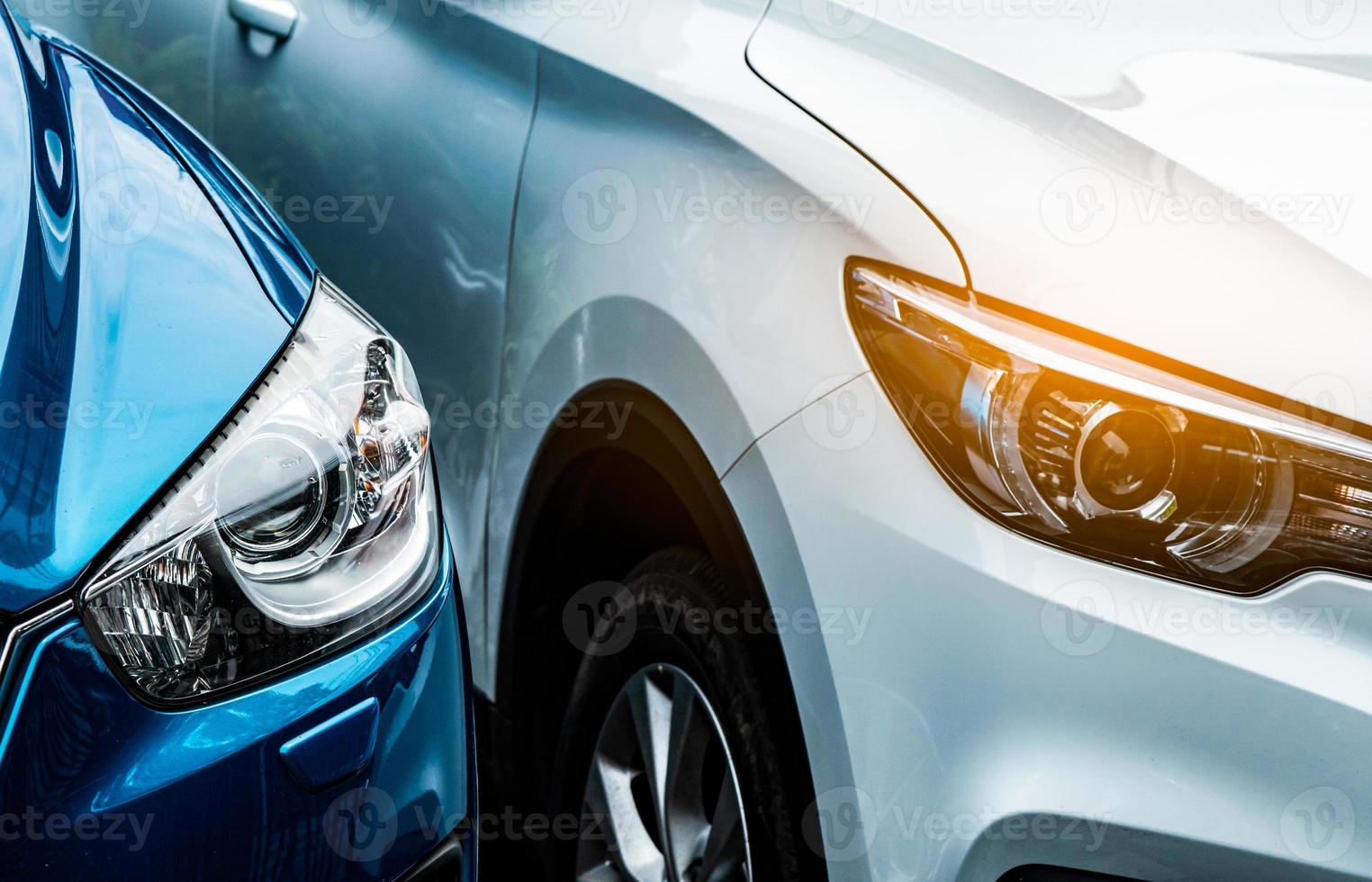 Close up headlamp light of blue and white SUV car. Blue car parked beside white car. Automotive industry concept. Electric or hybrid auto concept. Car service. Road trip adventure. Automobile rental. photo