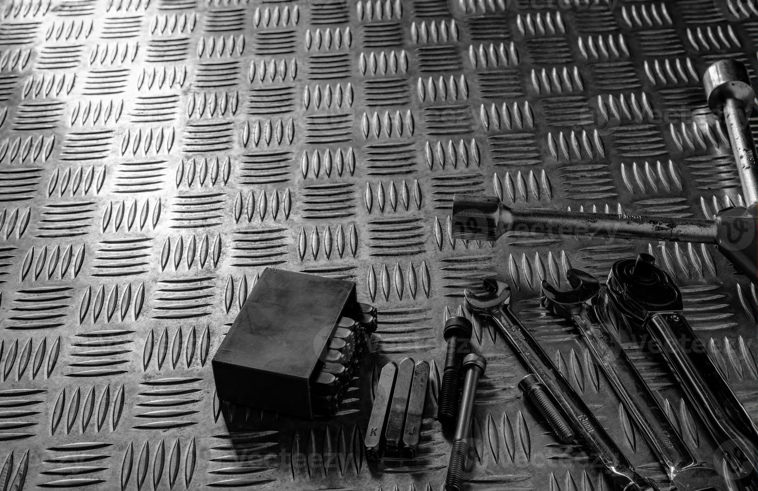 Tools on industrial metal checker plate. Metal checkerplate for anti skid. Wrench, and hex key on metal sheet floor. Silver bump ground with art pattern. Silver texture background. photo