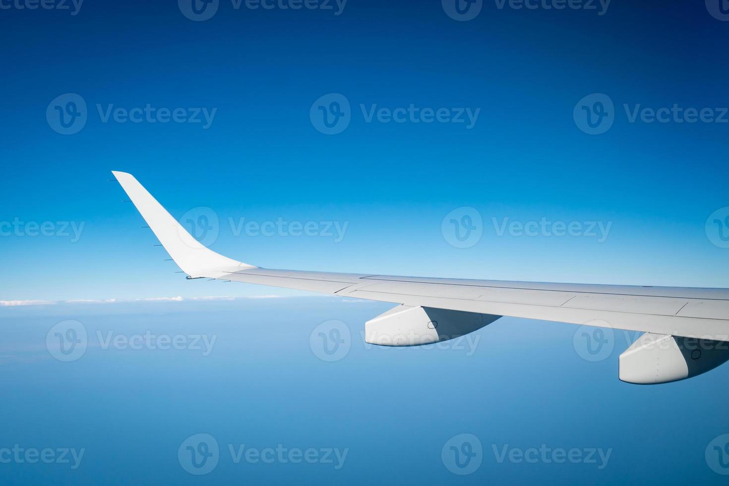 Wing of plane over white clouds. Airplane flying on blue sky. Scenic view from airplane window. Commercial airline flight. Plane wing above clouds. Flight mechanics concept. International flight. photo