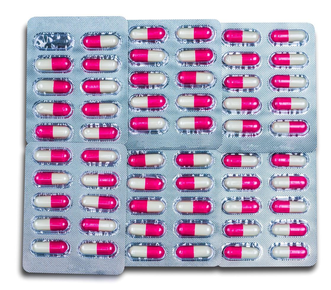 Top view of colorful antibiotic capsules pills in blister packs isolated on white background. Global health care and drug use with reasonable concept. Pink-white antimicrobial capsule pills. photo