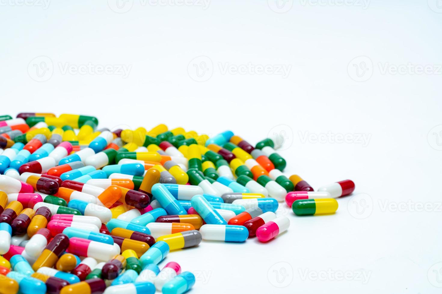 Selective focus on pile of multi-colored antibiotic capsule pills. Antimicrobial capsule pills on white background. Antibiotic resistance concept. Pharmacy drugstore products. Pharmaceutical industry. photo