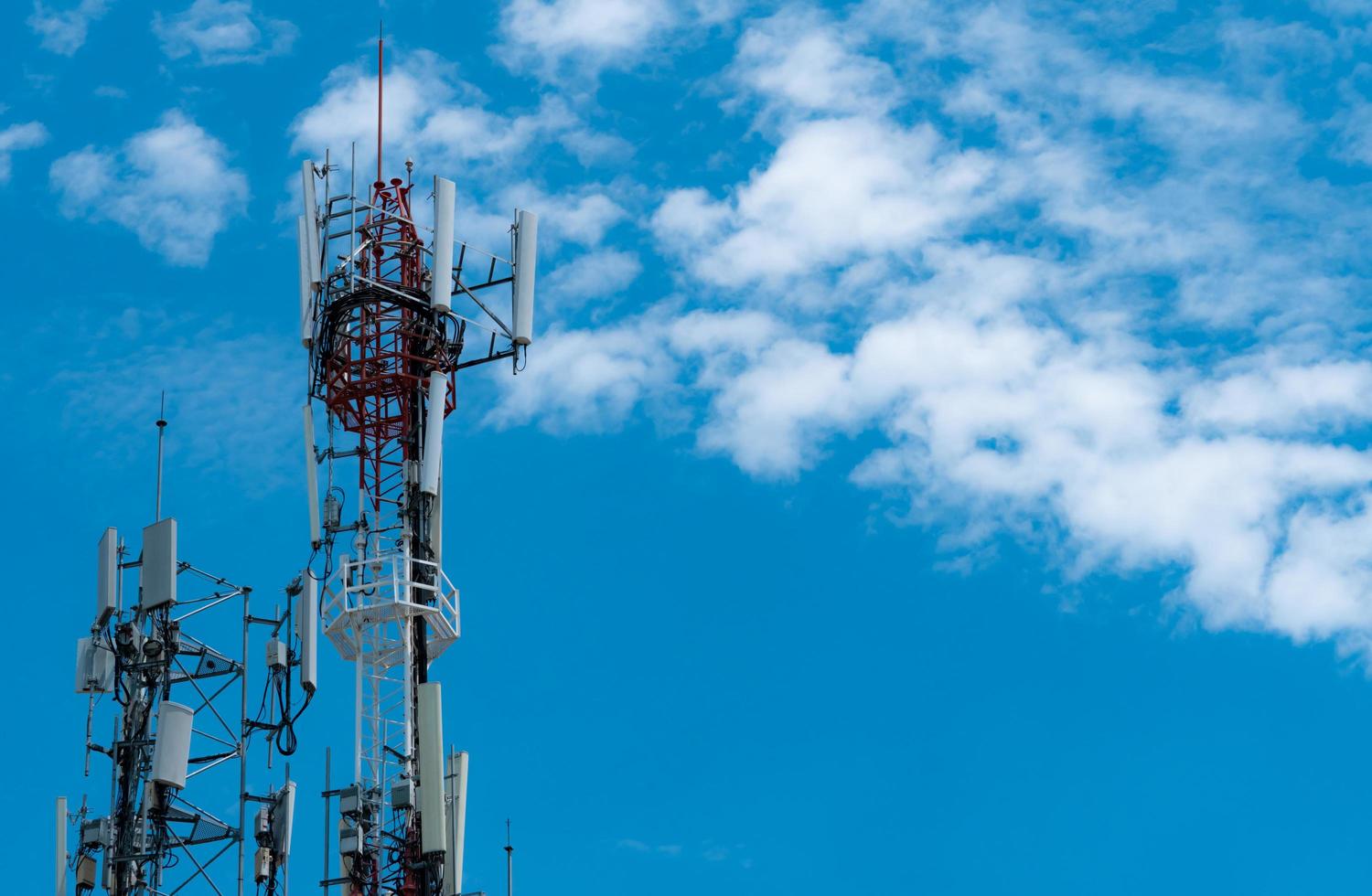 Telecommunication tower with blue sky and white clouds background. Antenna on blue sky. Radio and satellite pole. Communication technology. Telecommunication industry. Mobile or telecom 4g network. photo