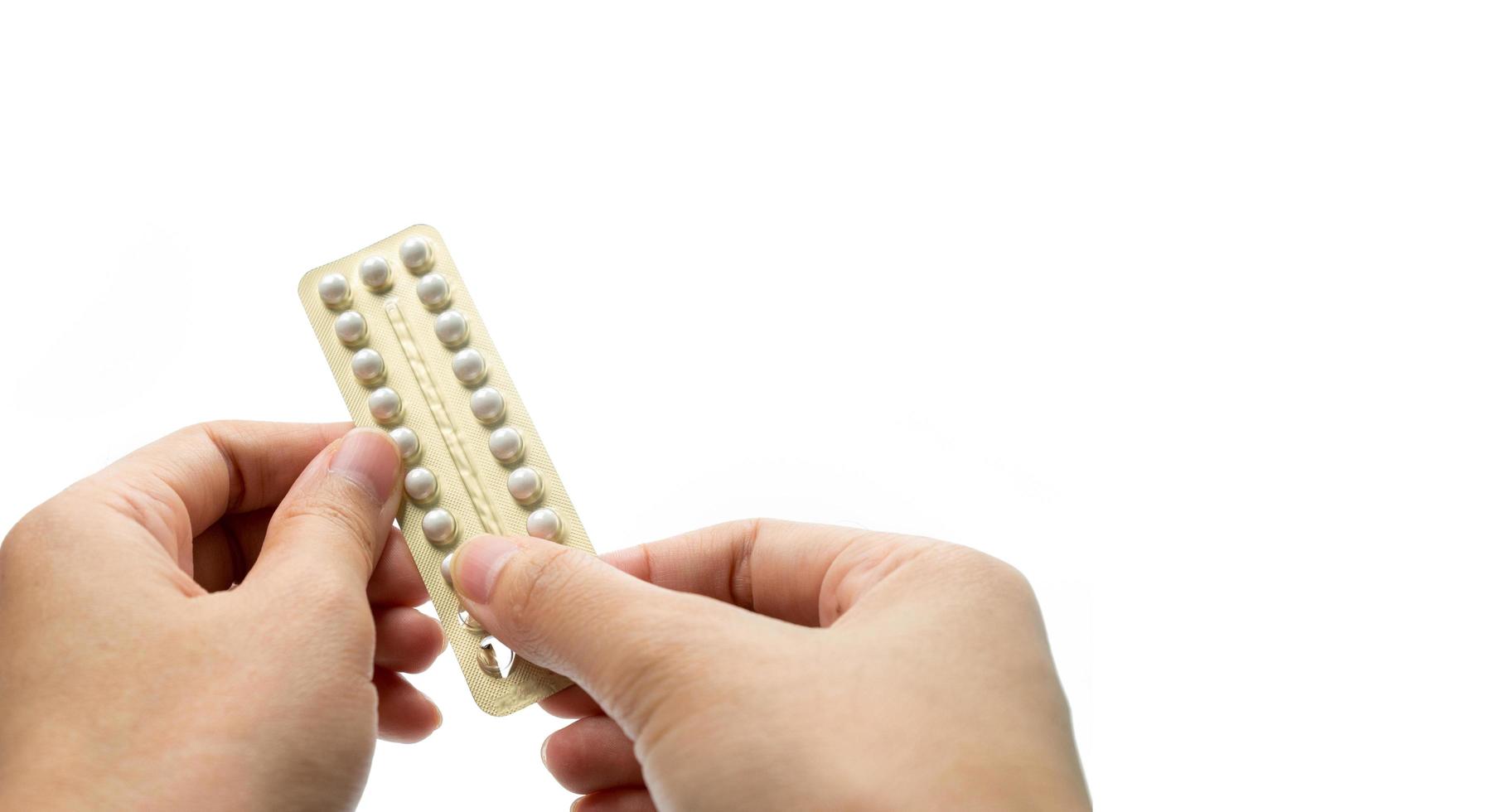Woman hand taking birth control pills. Asian adult woman holding pack of contraceptive pills isolated on white background with clipping path. Choosing family planning with birth control pill concept photo