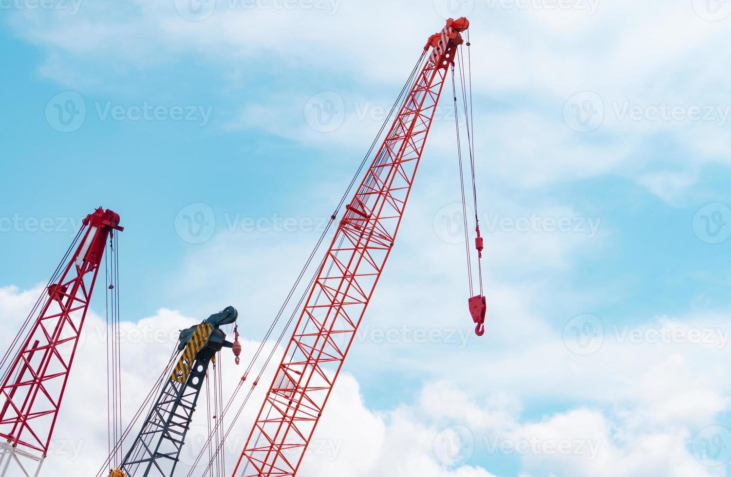 Crawler crane against blue sky and white clouds. Real estate industry. Red crawler crane use reel lift up equipment in construction site. Crane for rent. Crane dealership for construction business. photo