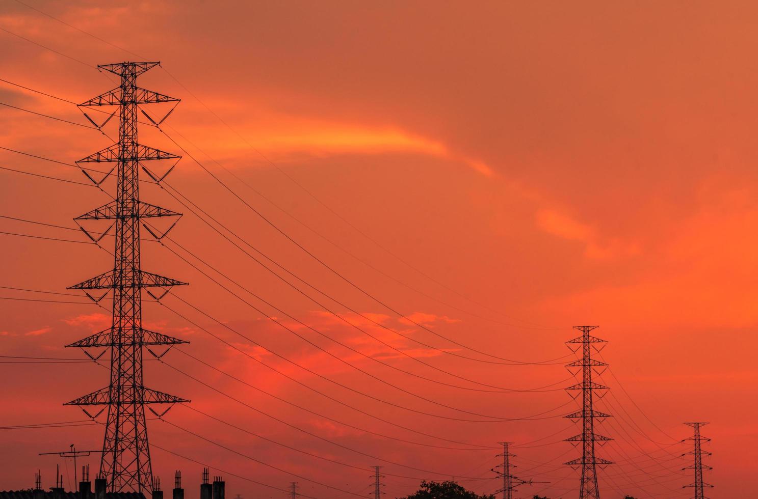 High voltage electric pole and transmission lines in the evening. Electricity pylons at sunset. Power and energy. Energy conservation. High voltage grid tower with wire cable at distribution station. photo