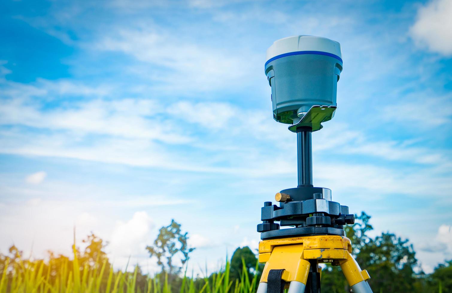 GPS surveying equipment on blue sky and white clouds background. GPS, GIS, and GNSS equipment. Land survey for map. Technology for marks land to made satellite map on the earth. Smart GNSS GPS survey. photo