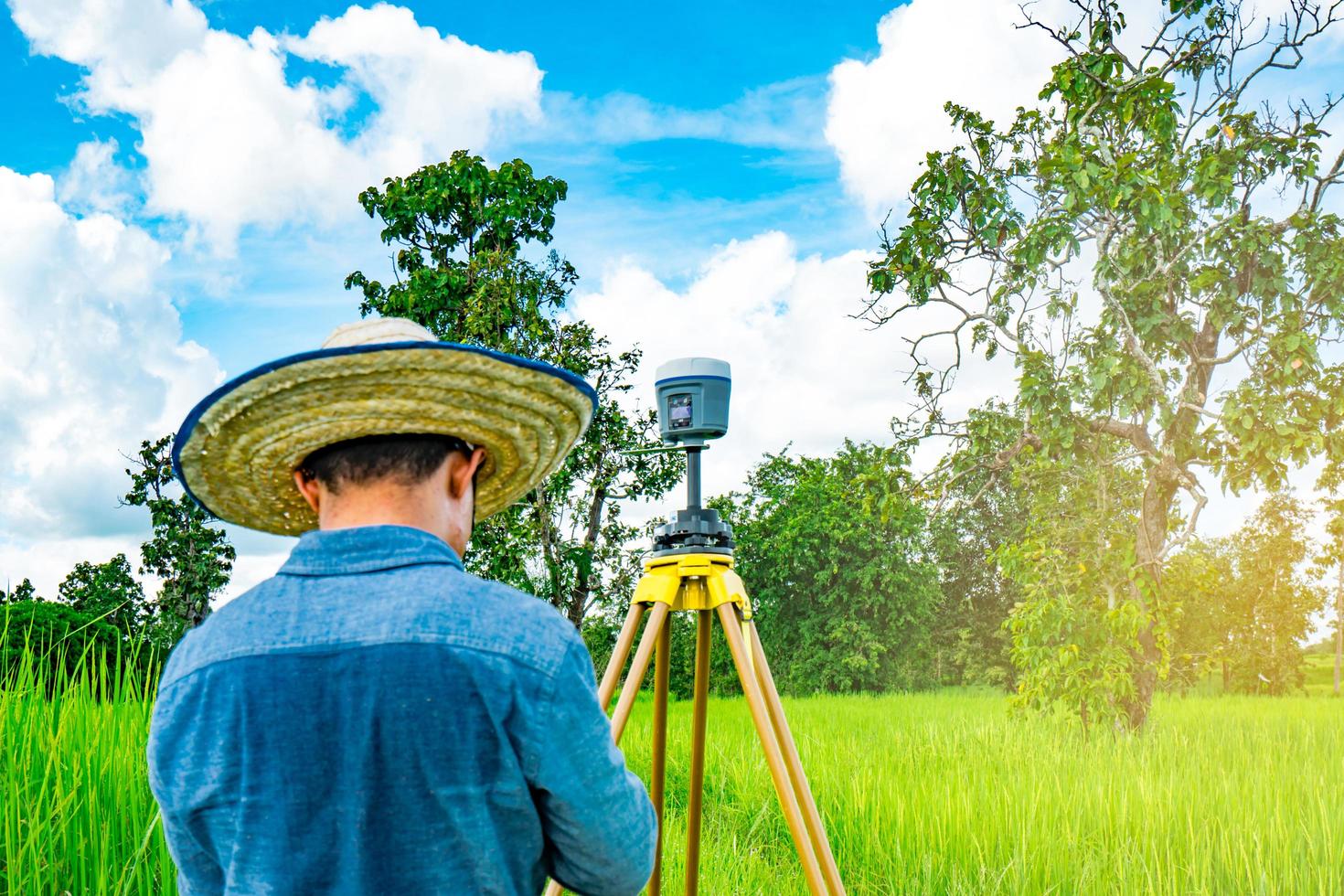 Asian smart engineer or surveyor working on controller screen for surveying land in rice field, Thailand. GPS surveying instrument. GPS equipment. Land survey for map. People work in good environment. photo