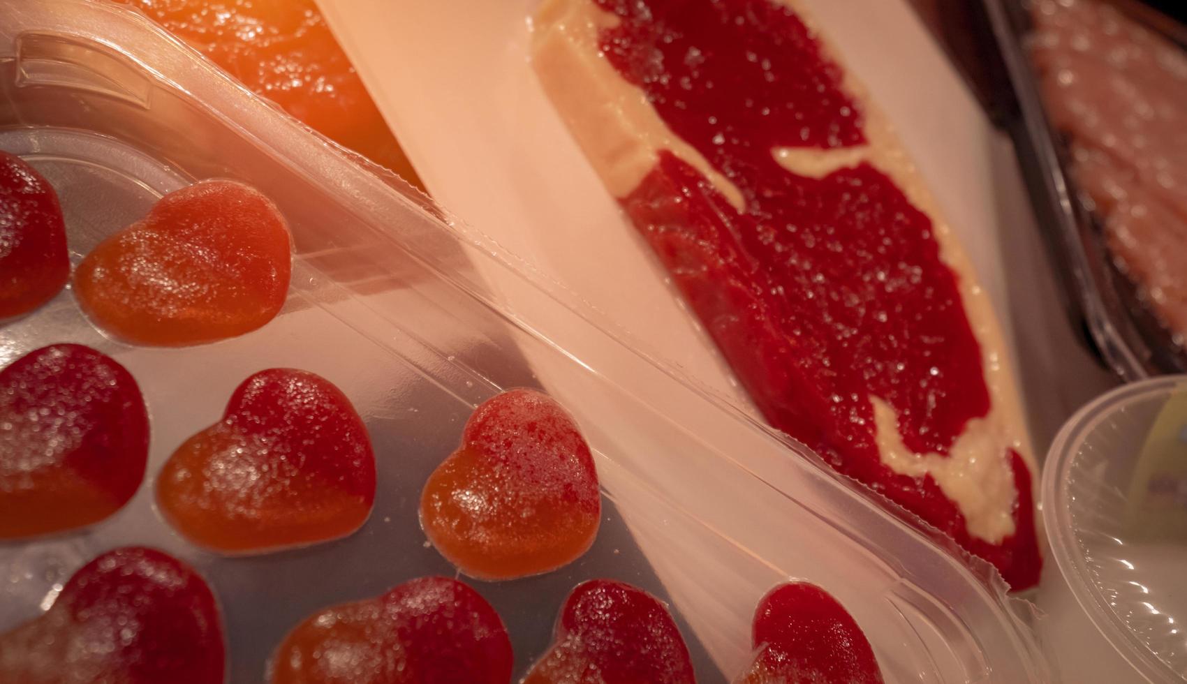 Skin pack or vacuum skin packaging. Meat and gummy candy in thin transparent plastic film. Skin pack for premium food packaging. Specialized food packaging technology for food industry manufacturing. photo
