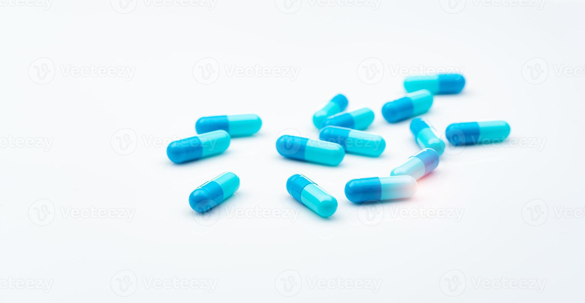 Blue antibiotic capsule pills spread on white background. Antibiotic drug resistance. Pharmaceutical industry. Healthcare and medicine concept. Health budget concept. Capsule manufacturing industry. photo