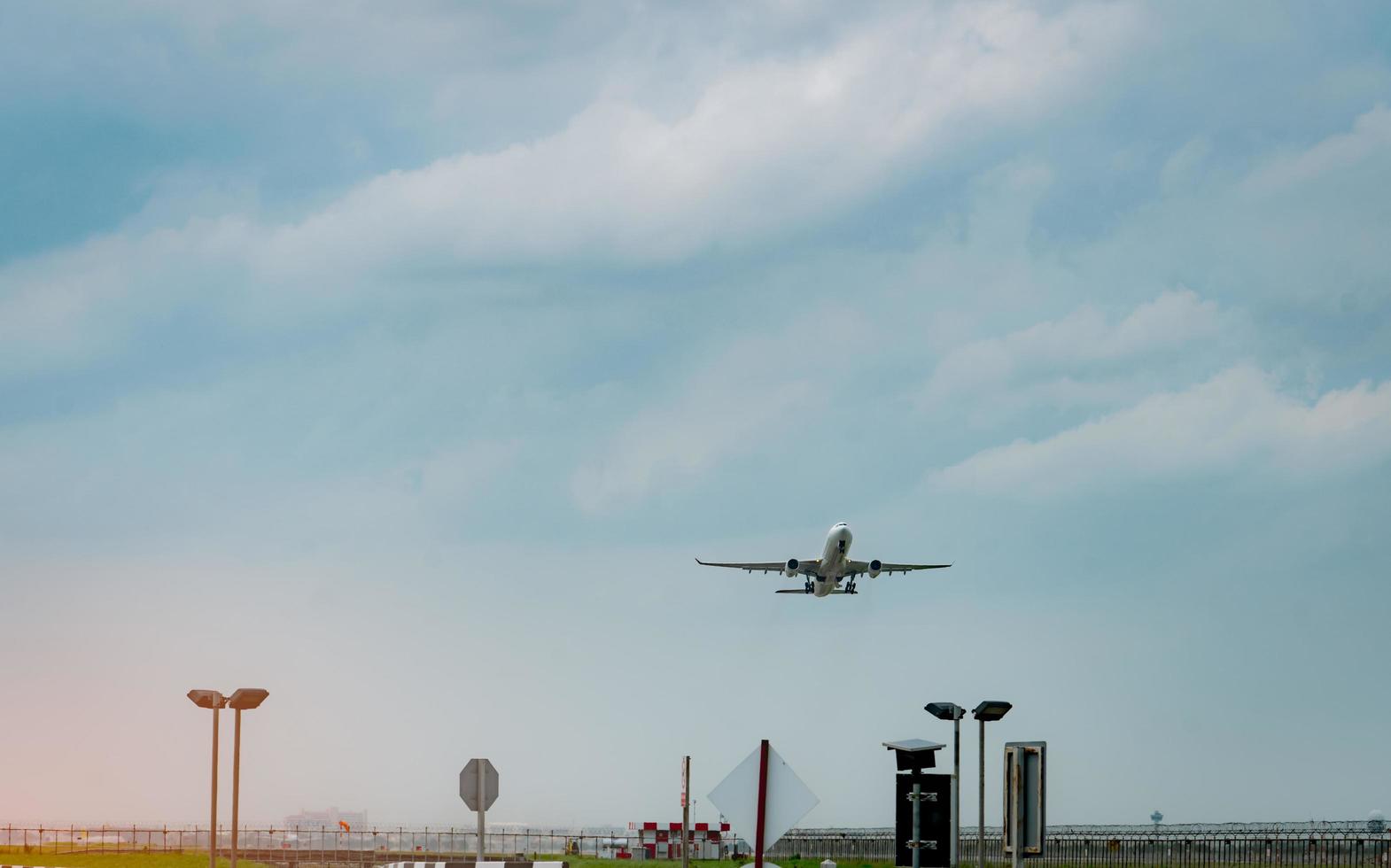 Passenger plane takes off at airport with beautiful blue sky and clouds. Leaving flight. Start the abroad journey. Vacation time. Fence and solar cell panels at the airport. photo