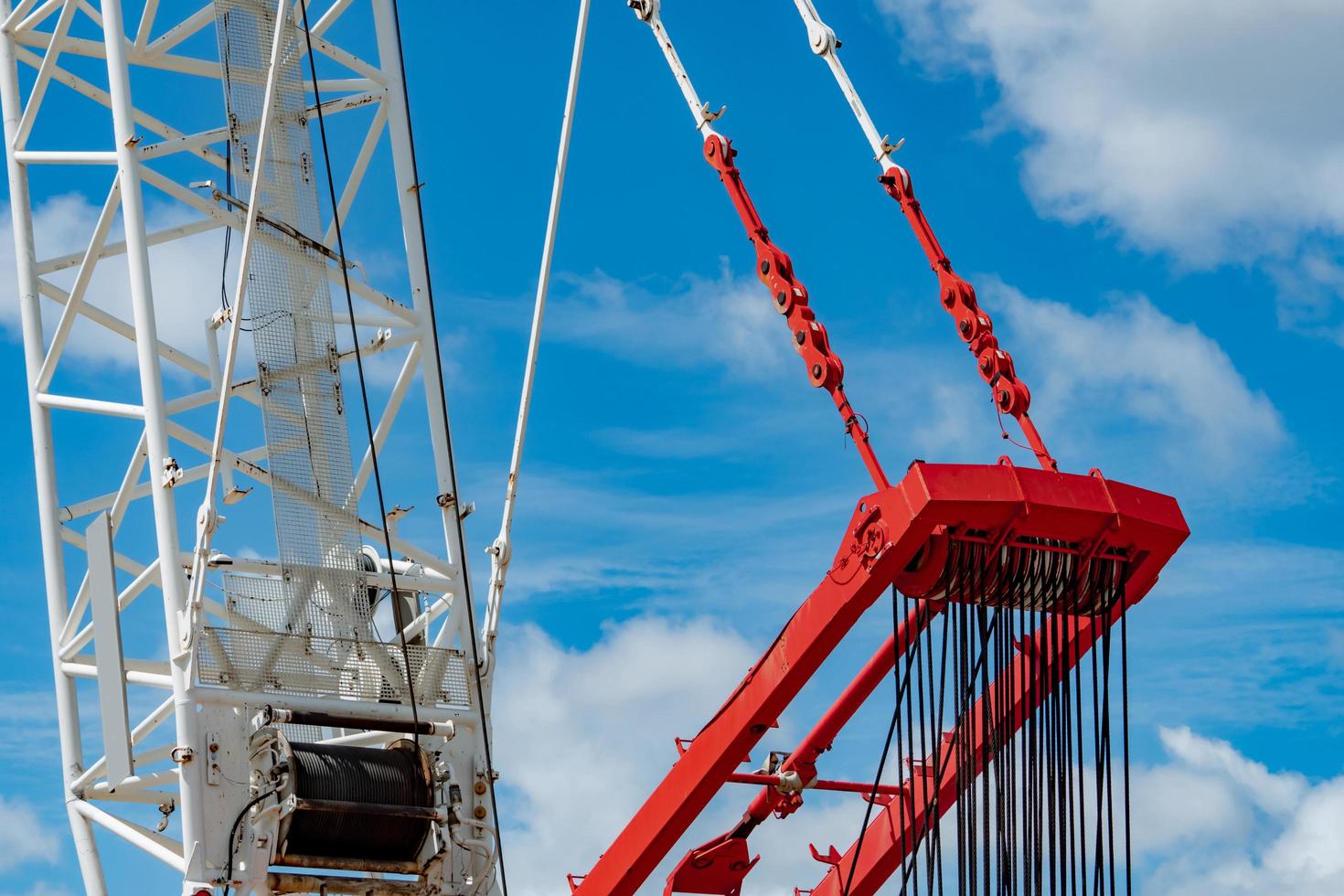 Closeup crawler crane with wire rope sling on crane reel against blue sky. Lifter equipment in construction site. Crawler crane for rent service. Heavy machinery mobile crane. Cable sling winch roll. photo