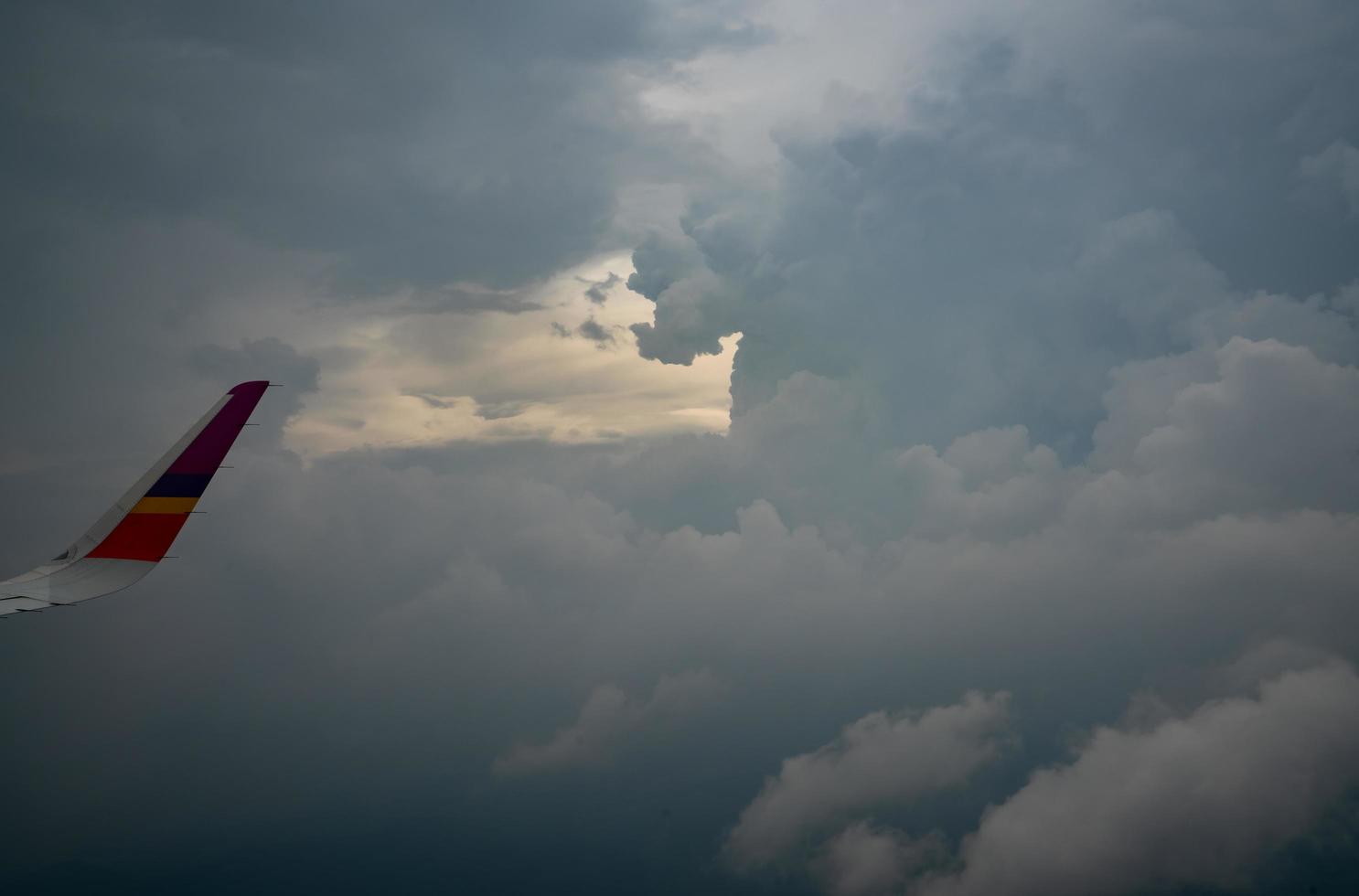 Wing of plane over the city. Airplane flying on blue sky. Scenic view from airplane window. Commercial airline flight in the morning with sunlight. Plane wing above clouds. Flight mechanics concept. photo