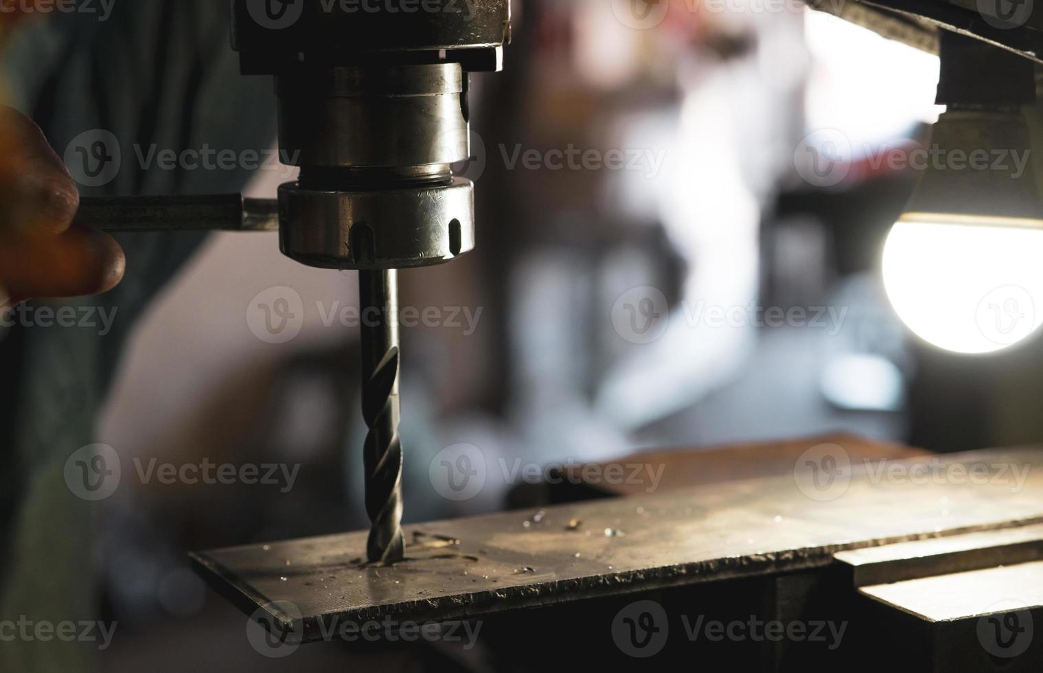 Worker hand working on milling machine to change metal drill bit. Tool for drilling metal workpiece. Milling machine. Steel manufacturing industry. Metal work industry. Industrial drilling machine. photo