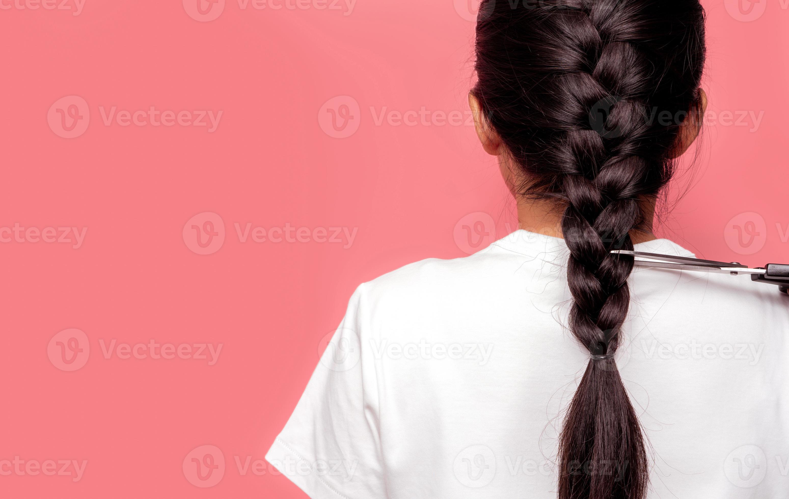 Back view of Asian woman with braided hairstyle is cutting with scissors for donate to cancer patients. Hair donation for breast cancer person. Woman with black long hair braid on pink background. Back view of Asian woman with braided hairstyle is cutting with scissors for donate to cancer patients. Hair donation for breast cancer person. Woman with black long hair braid on pink background.
