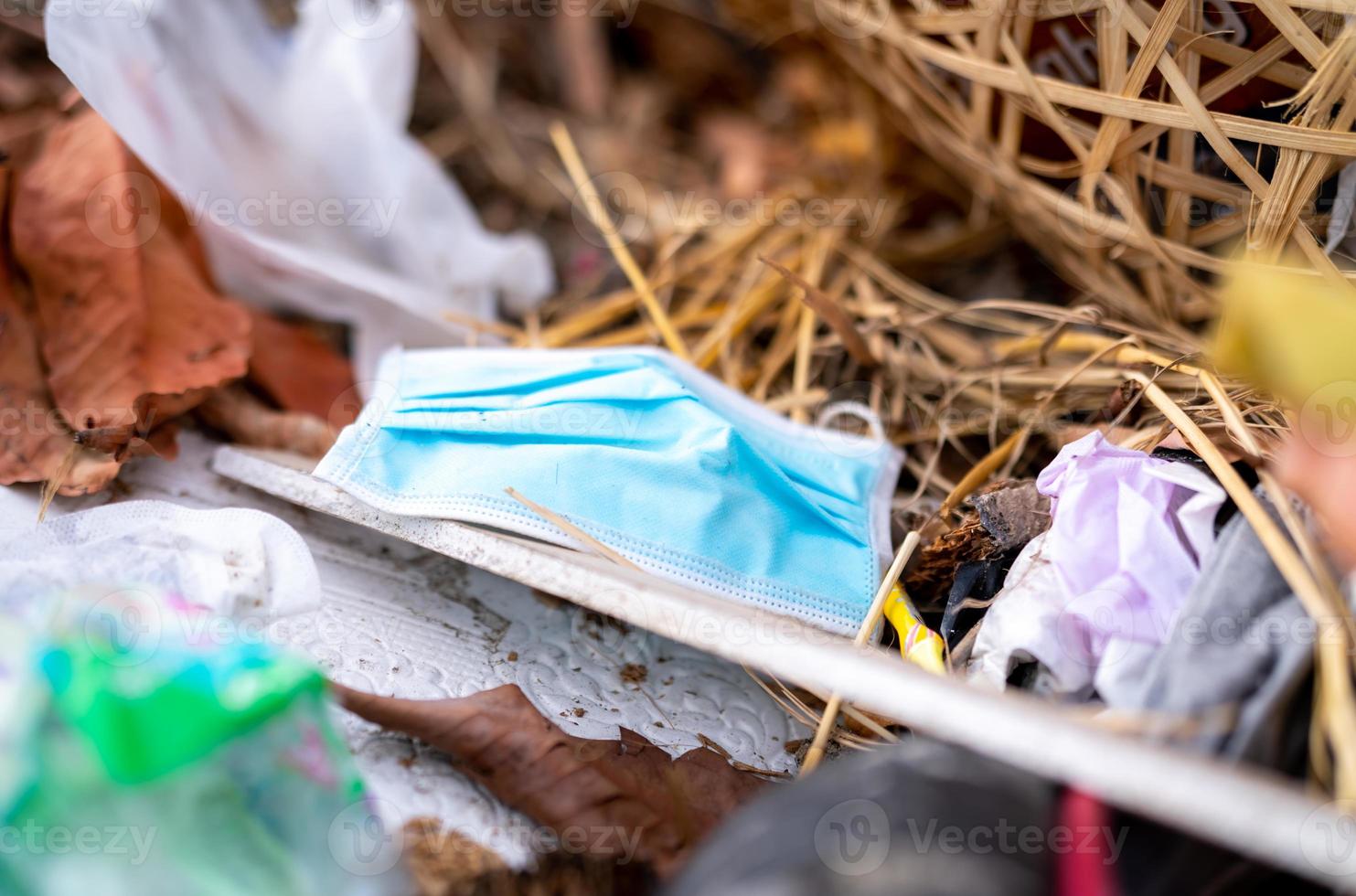 deseche la máscara facial usada en la basura doméstica. eliminación de desechos médicos con manejo antihigiénico. residuos contaminados en la comunidad. Mascarilla desechable con gancho para la oreja Basura de residuos en el suelo. impacto del coronavirus foto