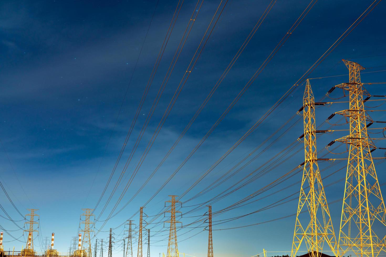 High voltage electric pole and transmission lines in the evening. Electricity pylons at night. Power and energy. Energy conservation. High voltage grid tower with wire cable at distribution station. photo