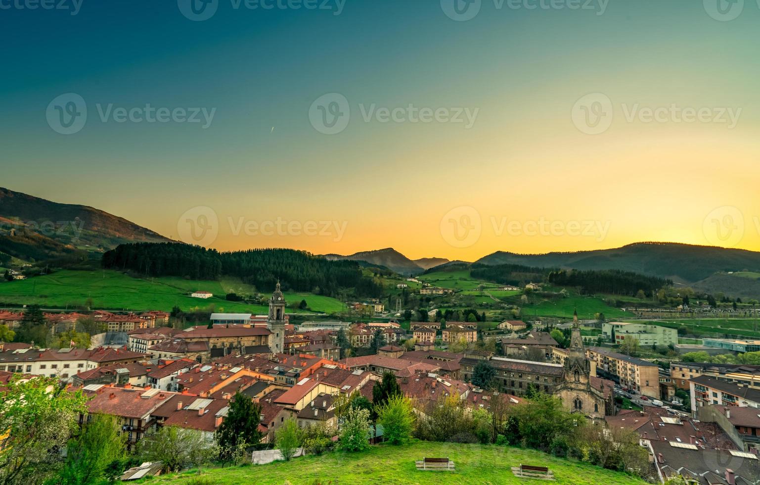 City in valley with morning sunlight. Yellow and blue morning sunlight sky over the mountain. Spring season in Europe. Green grass field and pine forest in rural village on the hill. Old city in Spain photo