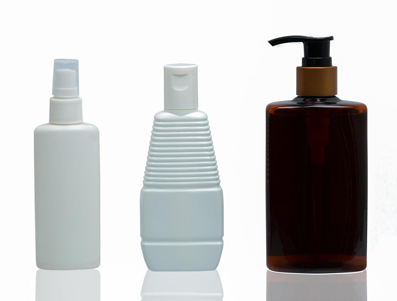 Three white and brown plastic cosmetic bottles with different type of cap  pump, spray and cap isolated on the white background with blank label and copy space photo