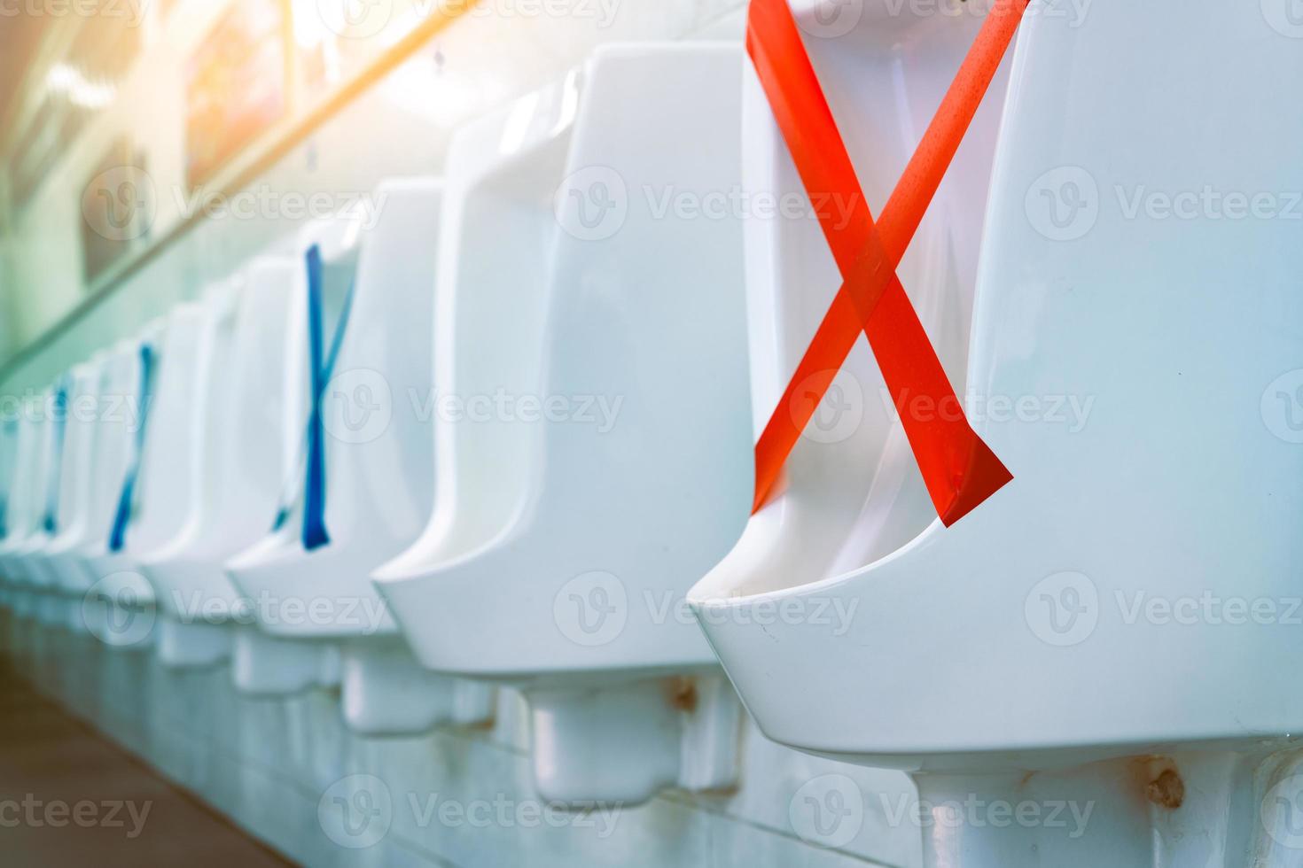 White ceramic urinals in men public toilet. Social distancing in men restroom to prevent coronavirus pandemic. Man bladder health with urinary incontinence problem. Urine infections. Male latrine WC. photo