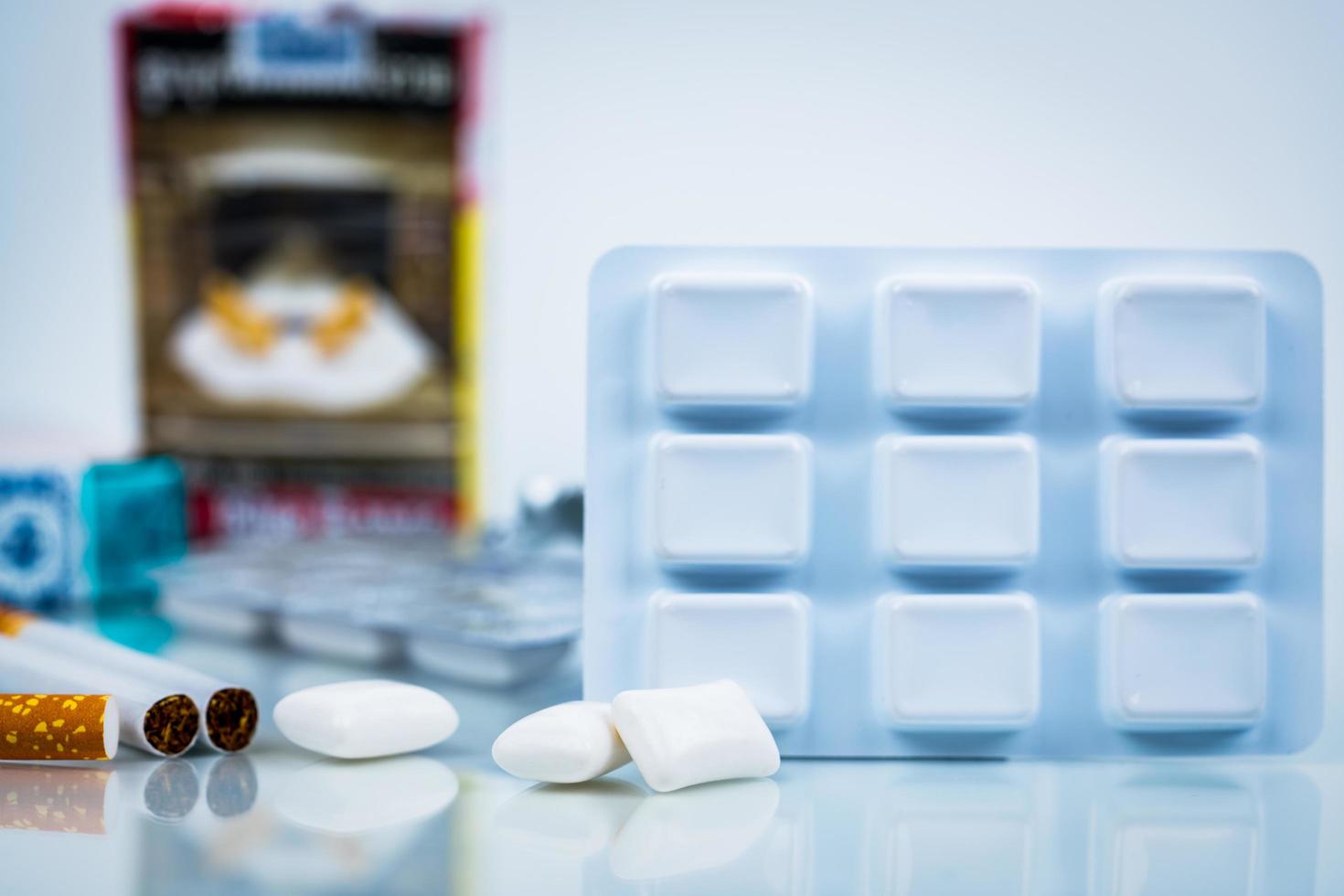 Nicotine chewing gum in blister pack on blurred background of cigarette pack.  Medicine for giving up smoking. World no tobacco day concept. photo